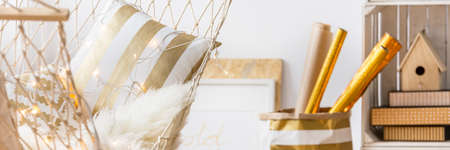 White hammock with stylish white and gold pillows in modern roomの写真素材