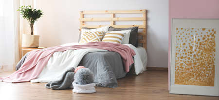 Cozy modern bedroom with wooden floor and grey and pink decor