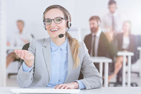 Positive hotline woman with glasses in bright office