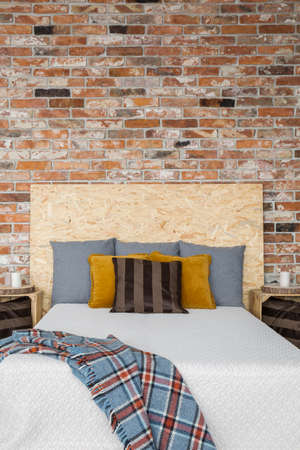 Cozy bedroom with red brick wall and wooden bedの写真素材