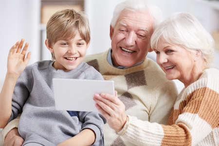 Happy grandparents and young grandson doing photo together with tablet