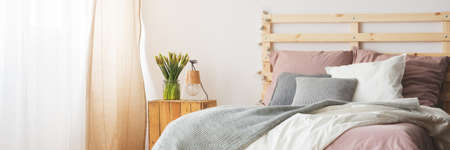 Comfortable cozy wooden bed with pink, white and grey colorsの写真素材