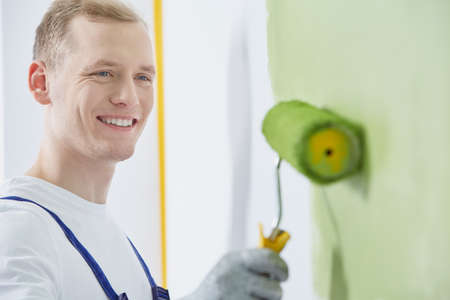 Young blond painter painting the wall in glovesの写真素材