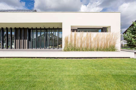 Exterior view of luxurious estate with lawn and decorative plantsの写真素材