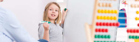 Girl during extra classes writing on a white boardの写真素材