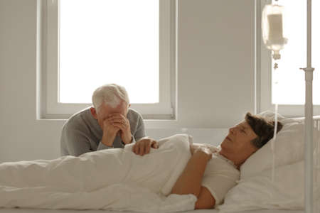 Despair elderly husband visiting his dying wife in hospitalの写真素材