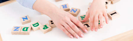 Close-up of teacher's and girl's hand placing the letters