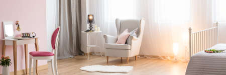 Spacious modern bedroom with white armchair and little dressing tableの写真素材