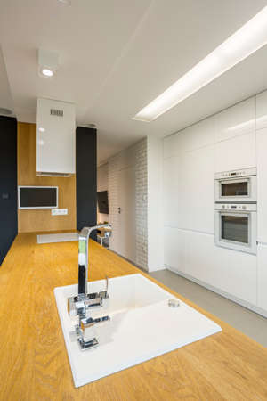 Sink in spacious white kitchen with wooden kitchen counterの写真素材