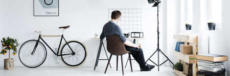 Panorama of hispter man sitting in modern vintage studioの写真素材