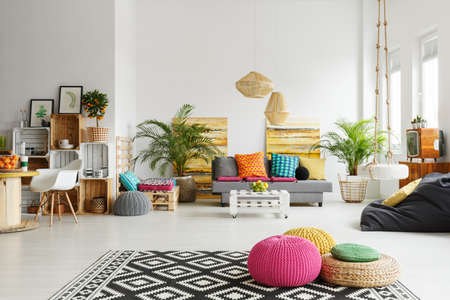 Loft living room with colorful poufs, sofa, carpet, crate furnitureの写真素材