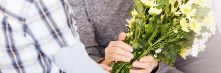 Close-up of grandmother getting flowers for birthday from grandsonの写真素材