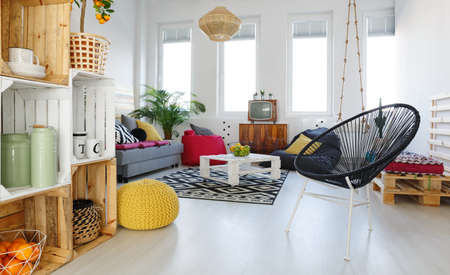 Living room with round chair, yellow pouf, sofa, pallet furnitureの写真素材
