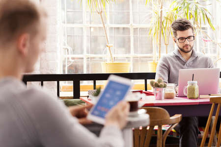 Handsome male hipsters having breakfast at cafe browsing the internet