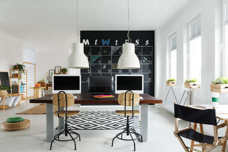 Bright interior with office desk, wood chair and computersの写真素材