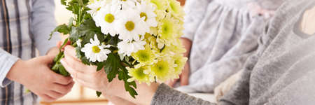Close-up of loving grandchild giving flowers for grandmother's day