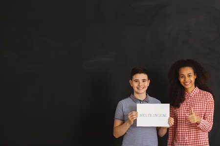 Smiling boy and woman holding card with multilingual inscription on itの写真素材