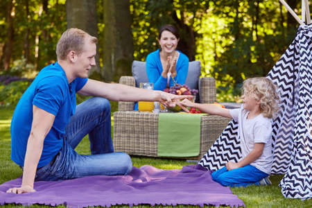Son and father playing rock-paper-scissors in the garden