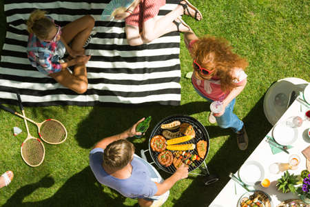 Young people spending summer afternoon doing barbecue in the gardenの写真素材