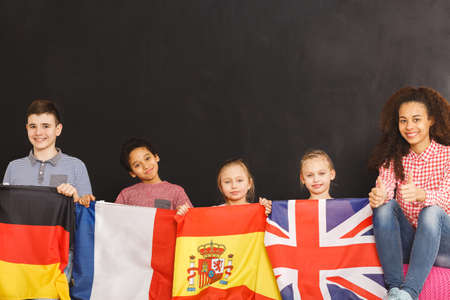 Smiling kids holding German, French, Spanish and British flagsの写真素材