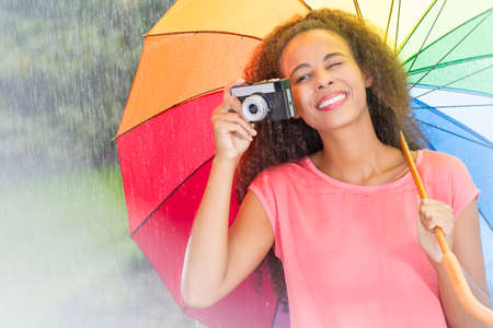 Afro american woman with colorful umbrella and cameraの写真素材