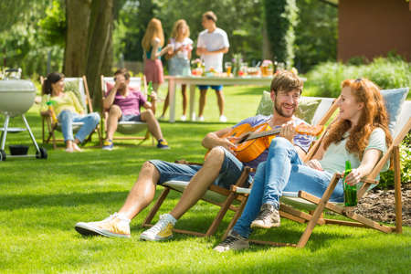 Young handsome man playing the guitar to his girlfriend
