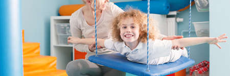 Smiling child exercising on a therapy swingの写真素材