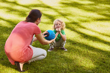Mother giving a rugby ball to her little sonの写真素材