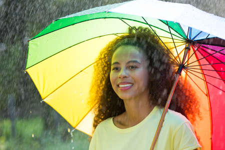 Afro american woman with umbrella in the summer rainの写真素材