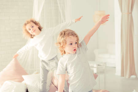 Two little brothers standing on the bed and having funの写真素材