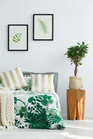White bedroom with leaf bedding and tree stump nightsandの写真素材