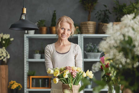 Smiling florist and bouquet if yellow tulips in sackの写真素材