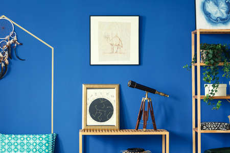 Blue room with wood furniture, wall posters, dreamcatcher, old telescopeの写真素材