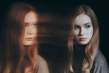 Beautiful, young woman with split personality, black backgroundの写真素材