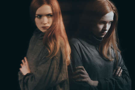 Angry, young woman having emotional problems, black backgroundの写真素材