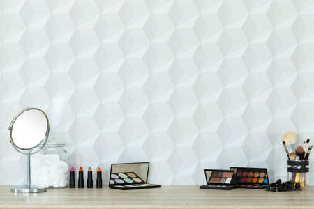 Colorful cosmetics and mirror lying on table, white backgroundの写真素材