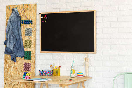 Modern workspace with brick wall, osb board, blackboard and chairの写真素材