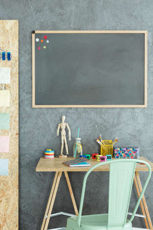 Dark workspace with osb desk and green chairの写真素材