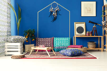 Oriental interior with colorful pattern pillows, blue wall, plants, rugの写真素材