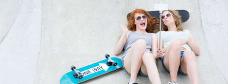 Joyful skate girls taking a selfie with skateboards