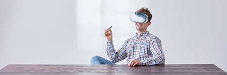 Young, creative man at the desk exposed to new technologies