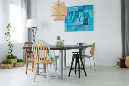 White dining room with plants, wood table, chairs and lamp