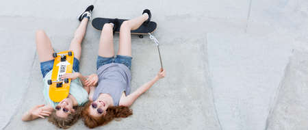 Happy teenagers lying with skateboards on the concrete construction of skateparkの写真素材