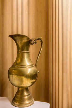 Close up of an antique golden jug isolated on a pattern wall backgroundの写真素材