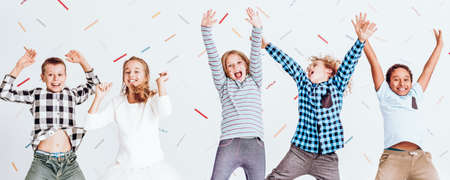 Cheerful girls and boys jumping with their hands upの写真素材