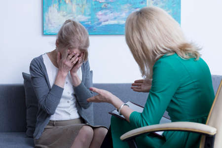 Worried woman crying on session with psychotherapistの写真素材