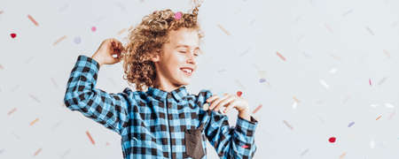 Smiling boy with curly hair having fun at the partyの写真素材