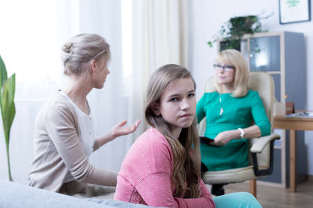 Worried mother, introverted daughter and psychotherapist during sessionの写真素材