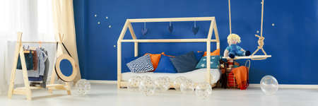 Cozy white and navy baby room with wooden bed and swingの写真素材