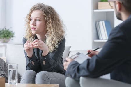 Sad attractive woman talking to psychotherapist during therapyの写真素材